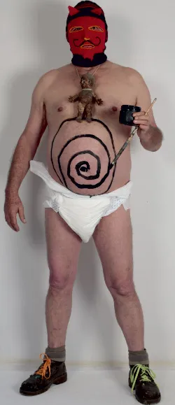 Memo Vélez disfrazado del padre Ubú, con máscara roja y la espiral pintada sobre el vientre